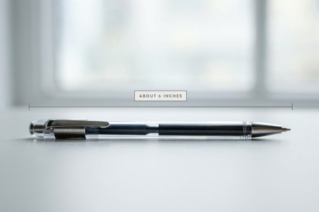 A ballpoint pen next to a dollar bill showing a similar length of about 6 inches