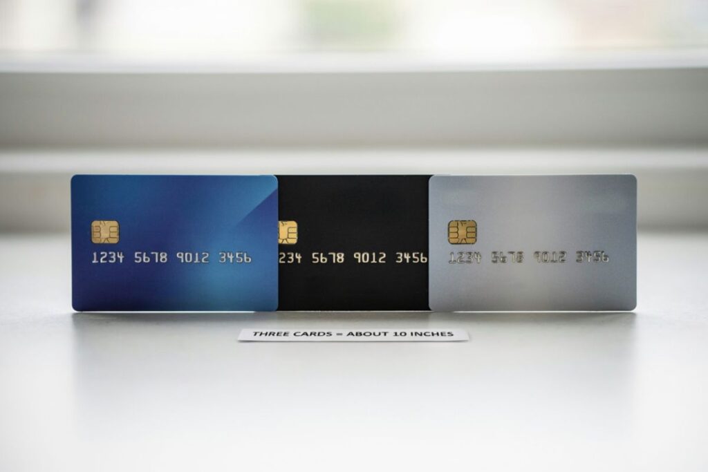 Three credit cards lined up end to end measuring about 10 inches long