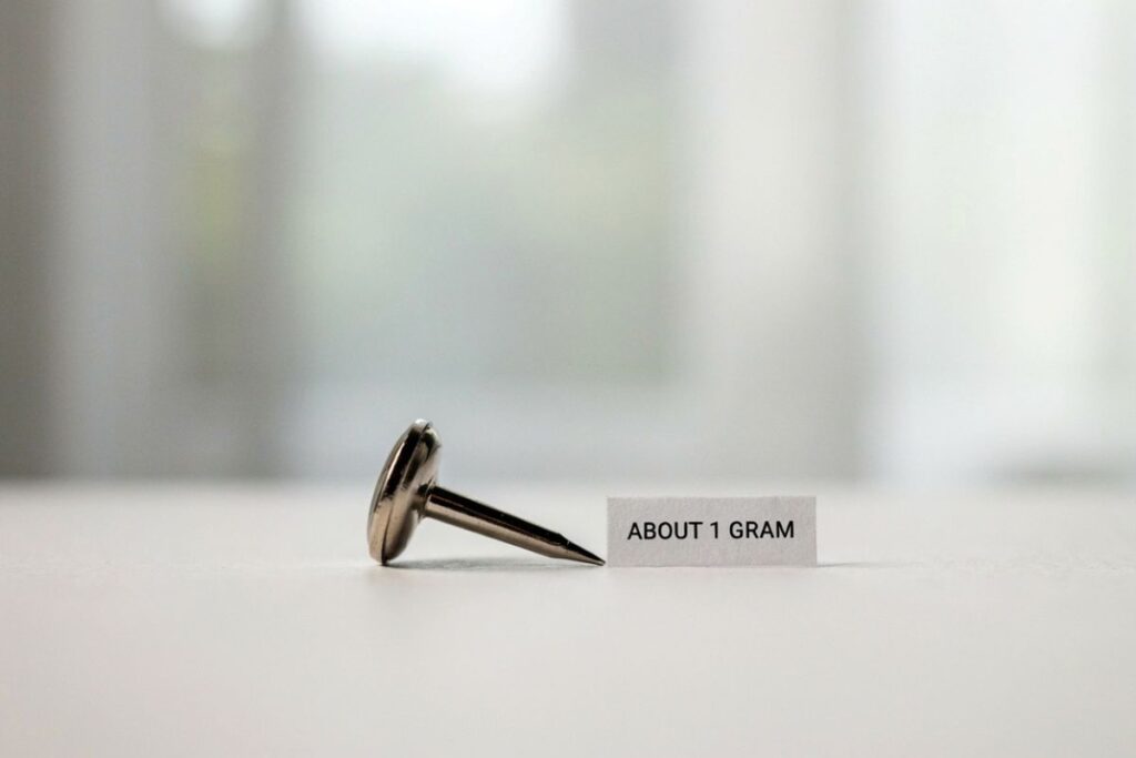 One metal thumbtack weighing about 1 gram as an office item reference